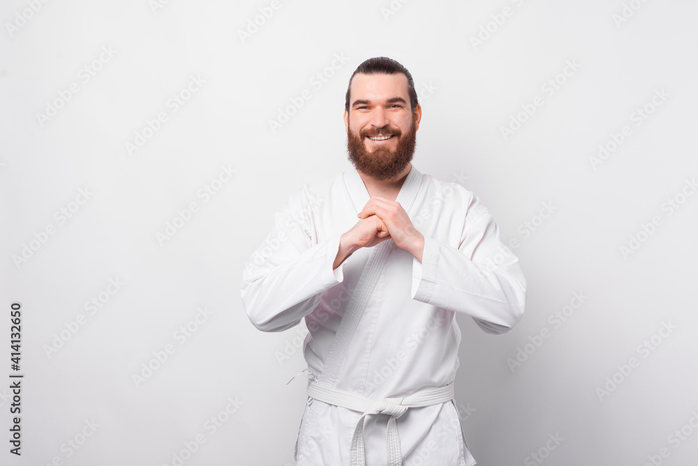 Portrait of cheerful bearded man saluting and wearing dobok. Portrait of cheerful bearded man saluting and wearing dobok.