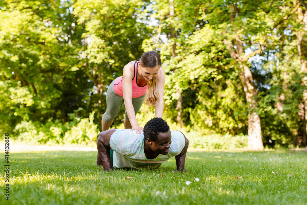 Mixed race couple doing fitness pushups in the park Mixed race couple doing fitness pushups in the park