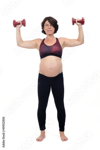 pregnant woman standing doing exercise dumbbells on white background