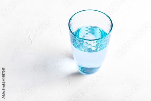 Blue glass of purified water on white