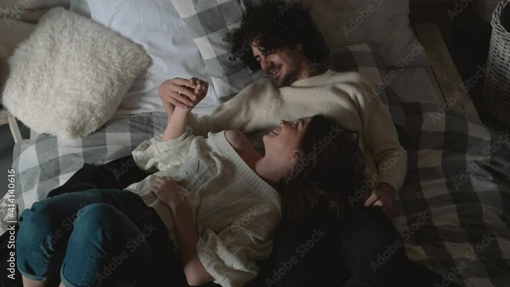 Young romantic cute couple lying in bed wearing winter clothes Young romantic cute couple lying in bed wearing winter clothes
