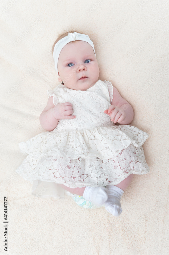 cute little baby girl in white dress lying on bed top view cute little baby girl in white dress lying on bed top view