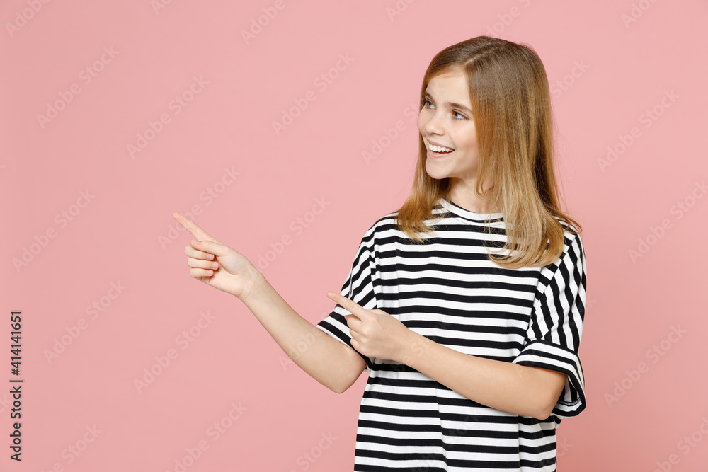 Little blonde smiling kid nice girl 12-13 years old wear striped oversized t-shirt point index finger aside on copy space area isolated on pastel pink background children. Childhood lifestyle concept. Little blonde smiling kid nice girl 12-13 years old wear striped oversized t-shirt point index finger aside on copy space area isolated on pastel pink background children. Childhood lifestyle concept.