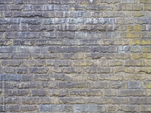 Wall with rough textured masonry covered with stains and darkened. Not seamless texture