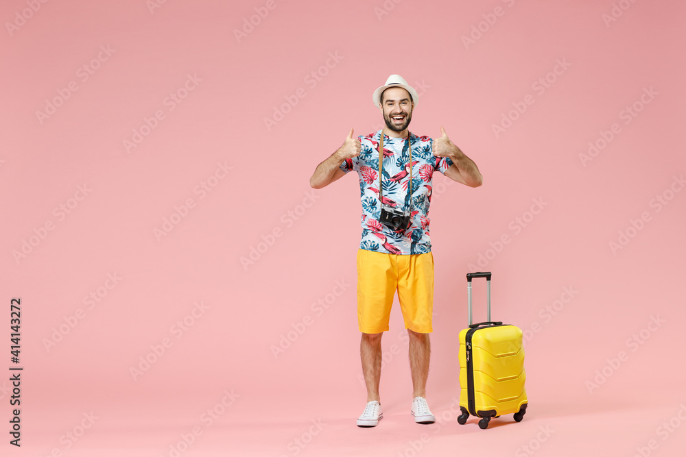 Full length of cheerful young traveler tourist man in summer clothes hat showing thumbs up like gesture isolated on pink background studio. Passenger travel on weekends. Air flight journey concept. Full length of cheerful young traveler tourist man in summer clothes hat showing thumbs up like gesture isolated on pink background studio. Passenger travel on weekends. Air flight journey concept.