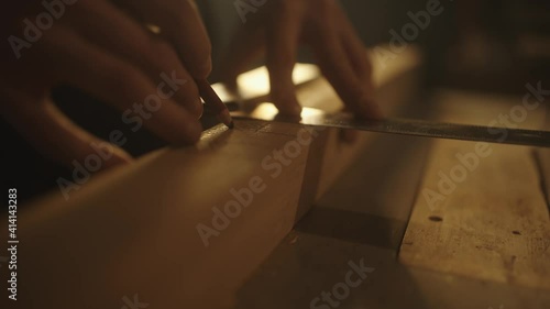 Carpenter checking wood plank's width for making a beautiful piece of furniture in his workshop.