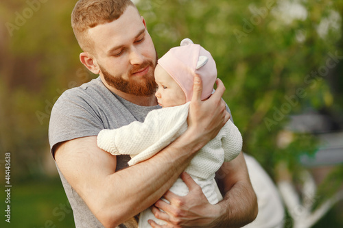 Family in a summer park. Father in a gray t-shirt. Cute newborn daughter.