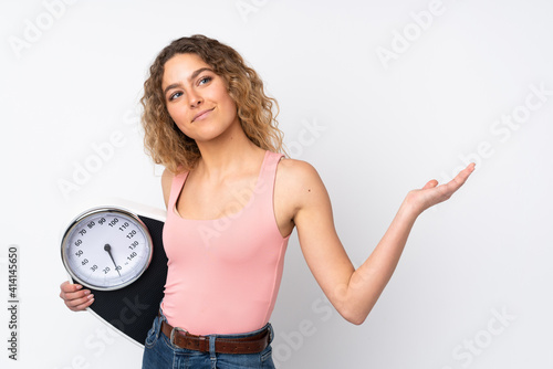Young blonde woman with curly hair isolated on white background with weighing machine