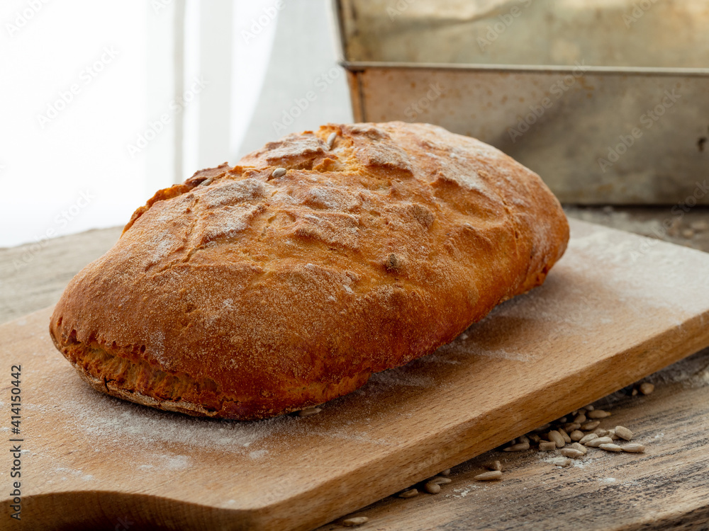 Bread, freshly baked at home, put on a wooden board and in a metal form.