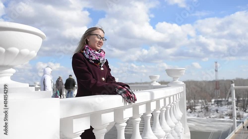 a girl in a burgundy coat stands on the street in a sunny windy weather and smiles. a walk in the fresh air after the end of the pandemic. photo