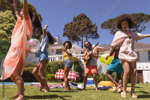 Diverse group of friends dancing and smiling at a pool party