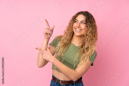 Young blonde woman with curly hair isolated on pink background pointing with the index finger a great idea © luismolinero