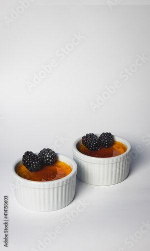 Creme Brûlée with fresh Blackberries. Photo was taken with white background and single light source gourmet style.