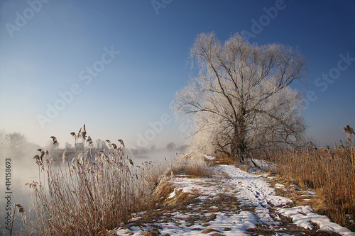 Spring landscape with a river covered with fog, melting snow on the river bank, trees