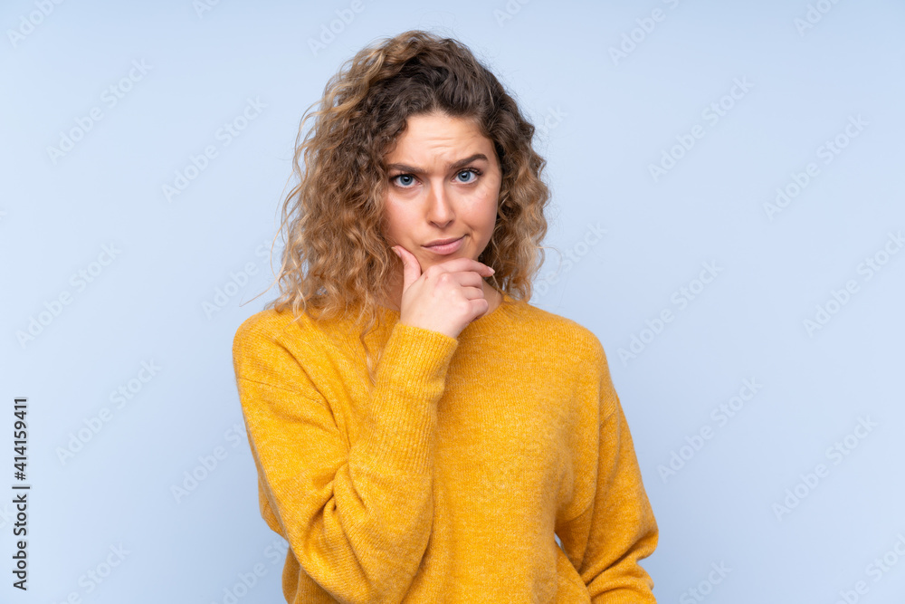 Young blonde woman with curly hair isolated on blue background thinking Young blonde woman with curly hair isolated on blue background thinking