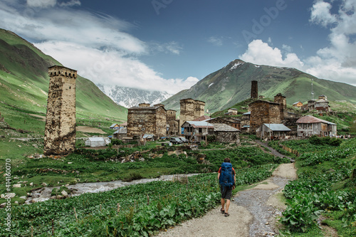 Happy male traveller in Ushguli,UNESCO site,Georgia.Backpacker exploring the Greater Caucasus mountains.Rural stone houses,village life,wild pure nature.Popular travel destination.Wanderlust man. photo
