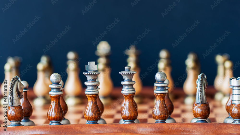 Wooden black and white pieces on chess board. Beginning of game, selective focus Wooden black and white pieces on chess board. Beginning of game, selective focus