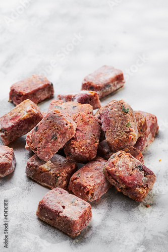 Composition with raw square cutlets on light background. Natural food for dogs. BARF dog diet