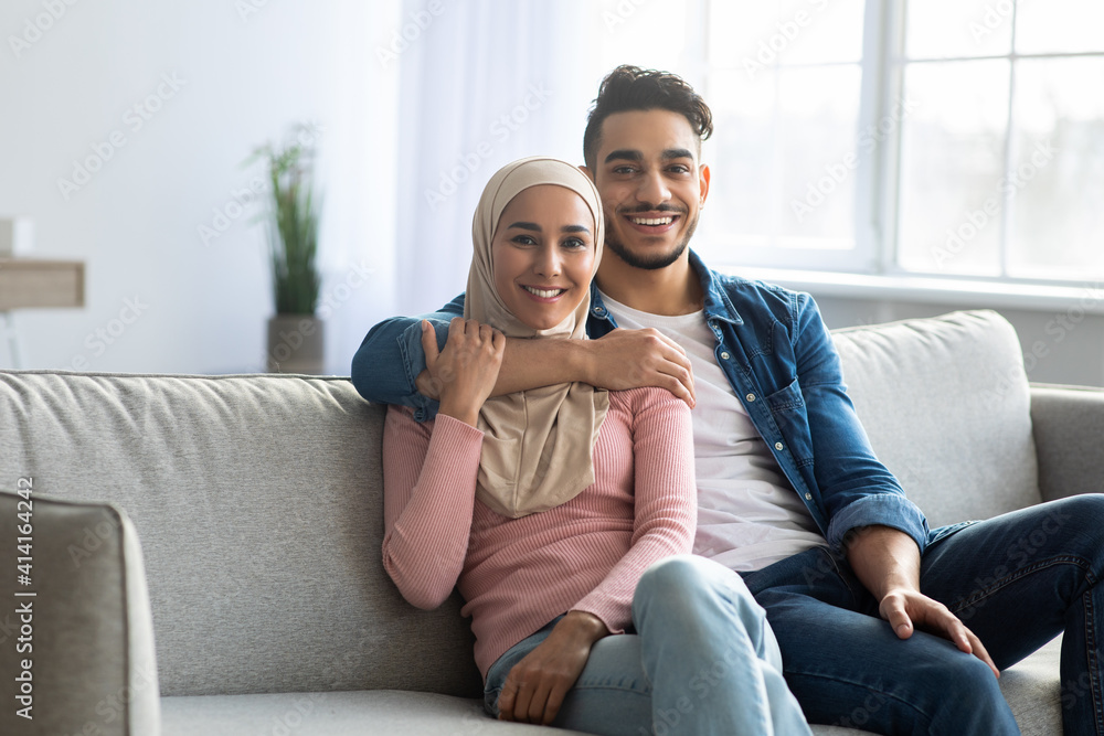 Obraz premium Positive arab couple posing on couch at home