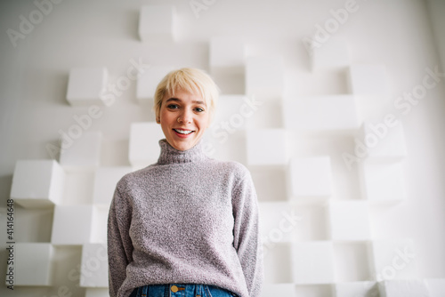 Happy woman near wall with cube decorations