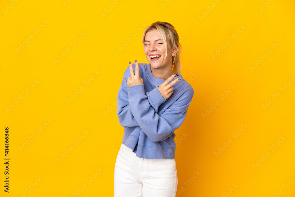 Young Russian woman isolated on yellow background smiling and showing victory sign Young Russian woman isolated on yellow background smiling and showing victory sign