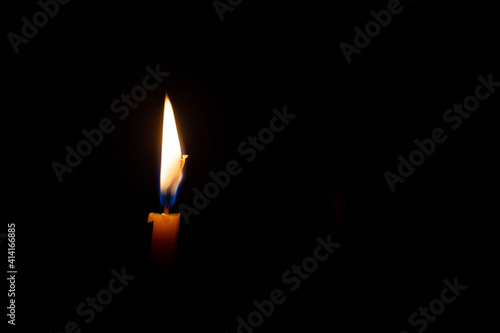 Burning candle isolated on black background with space for text. Concept of mourning, sadness, sorrow. Commemoration day.