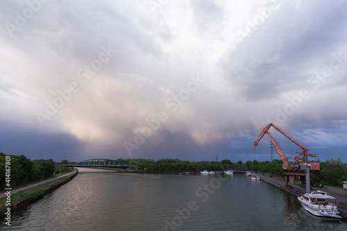 painting a rainbow in the blue sky above the river port with an old crane