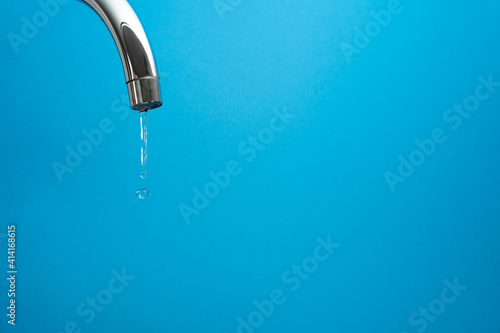 water coming out of a tap on blue background. Whith copyspace
