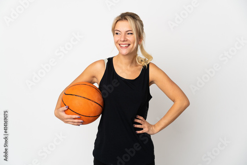 Young Russian woman playing basketball isolated on white background posing with arms at hip and smiling