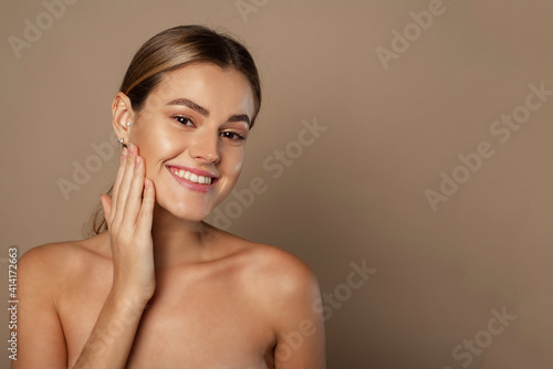 Beauty young woman touches her face with her hands. Young pretty lady with natural makeup on beige background. Beauty, Spa and Skin care concept