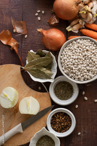 Traditional cuisine - raw beans and seasoning on wooden background