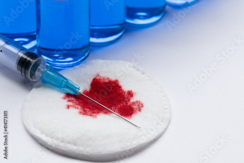 Blood medical cotton wool. Medical syringe with a needle and an ampoule of vaccine. The concept of taking blood for analysis or vaccination against coronavirus