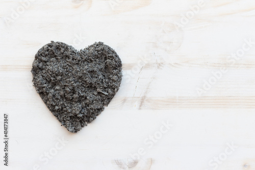 Heart of ashes on white wood background