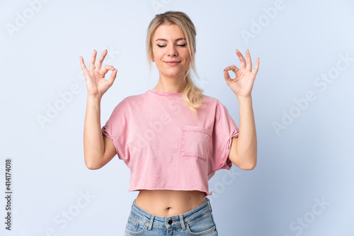 Blonde woman over isolated blue background in zen pose