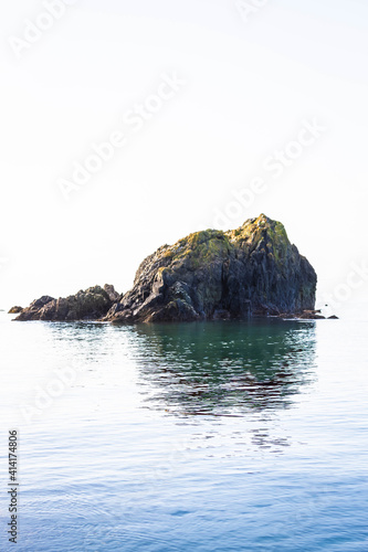A single rock protruding from the surrounding blue ocean waters.