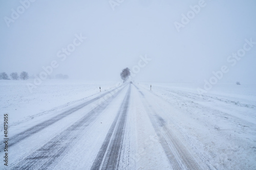Schneebedeckte Straße bei Schneesturm im Winter mit Baum © Tobias