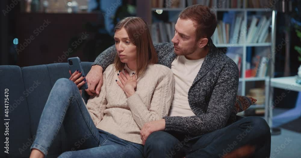 Caucasian couple of wife and husband communicasting online on mobile phone videocall. Unhappy young woman learning bad news talking webcam wirh family. Caucasian couple of wife and husband communicasting online on mobile phone videocall. Unhappy young woman learning bad news talking webcam wirh family.