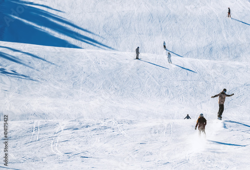 Skiers riding down a slope on a sunny day at a ski resort.