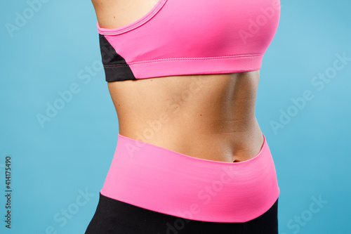 Fitness girl shows a beautiful pumped up press on a blue background. 