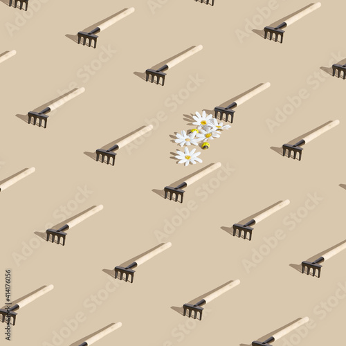 Daisy and garden rake creative minimal background. Neutral beige table with sunshine and hard shadow. Garden, floral, season pattern