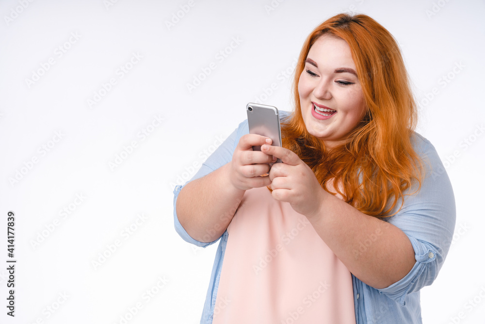 Happy young corpulent woman in casual outfit using smart phone isolated over white background Happy young corpulent woman in casual outfit using smart phone isolated over white background