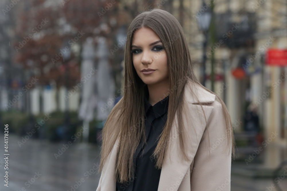 Outdoor portrait of young stylish woman in camel coat in the city on a rainy day Outdoor portrait of young stylish woman in camel coat in the city on a rainy day