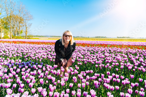 Photography Beautiful Woman with blond hair standing in colorful tulip flower fields in Amsterdam region, Holland, Netherlands