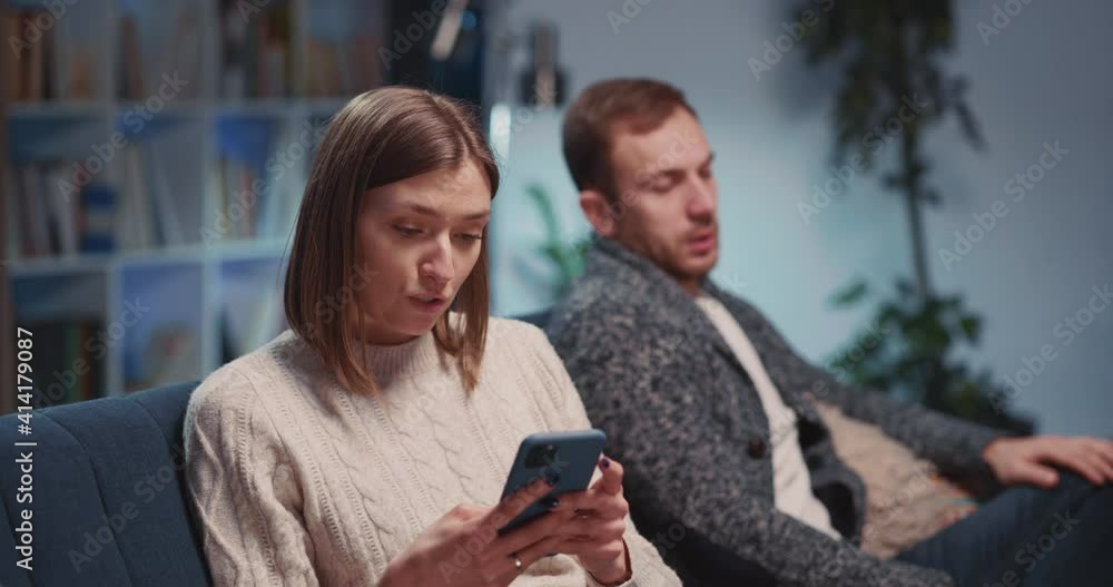 Argued Young Angry Caucasian Couple Making Conflict Agruing wih Each Other Using Mobile Phones Sitting Separately in Living Room. Quarrel. Argued Young Angry Caucasian Couple Making Conflict Agruing wih Each Other Using Mobile Phones Sitting Separately in Living Room. Quarrel.