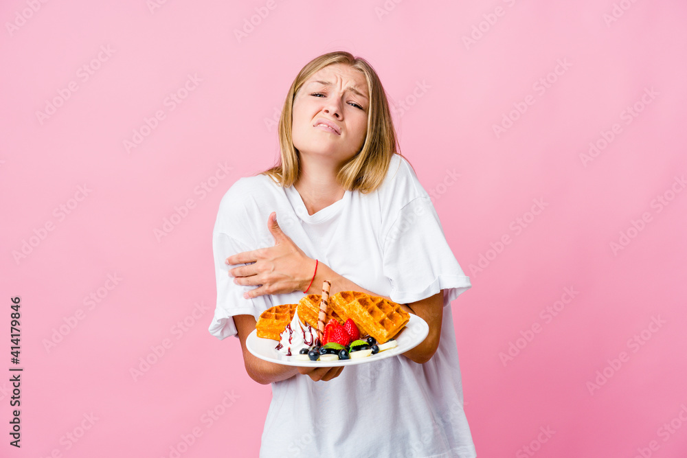 Young russian woman eating a waffle isolated going cold due to low temperature or a sickness.