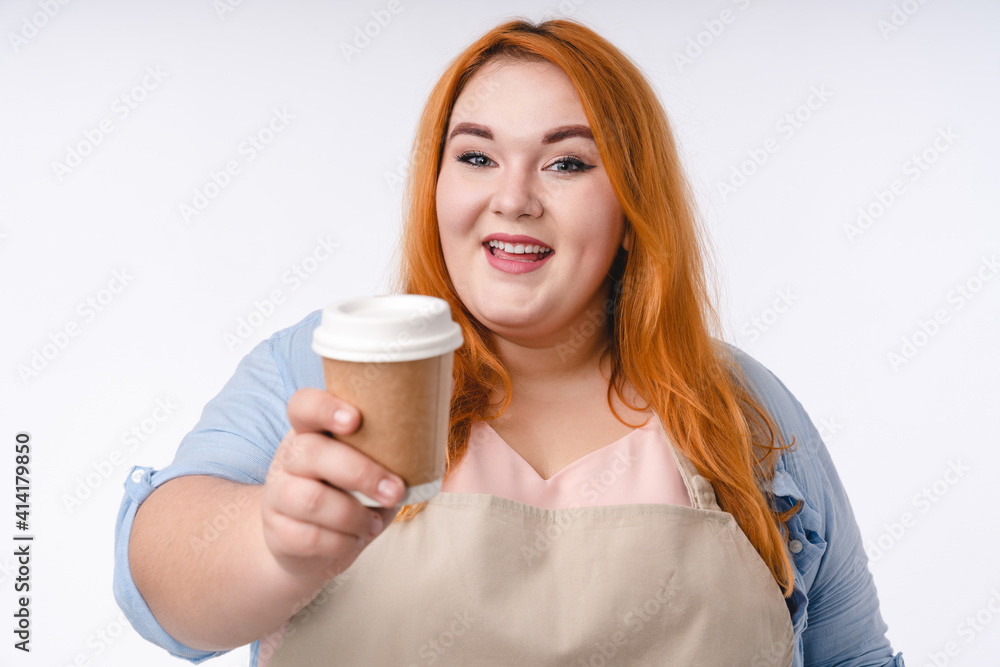 Close-up portrait of a young overweight woman barista handing a cup of hot drink isolated in white Close-up portrait of a young overweight woman barista handing a cup of hot drink isolated in white