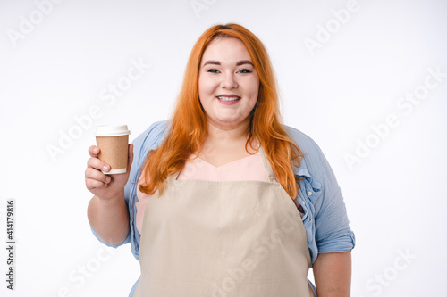 Smiling overweight woman barista with a cup of hot drink isolated over white background