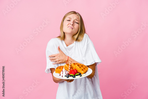 Young russian woman eating a waffle isolated going cold due to low temperature or a sickness.