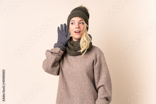 Young woman with winter hat over isolated background listening something © luismolinero