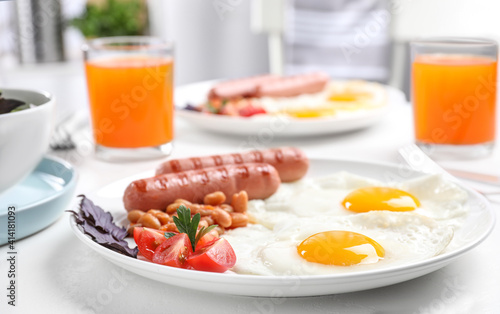 Delicious breakfast with fried eggs and sausages served on white table, closeup